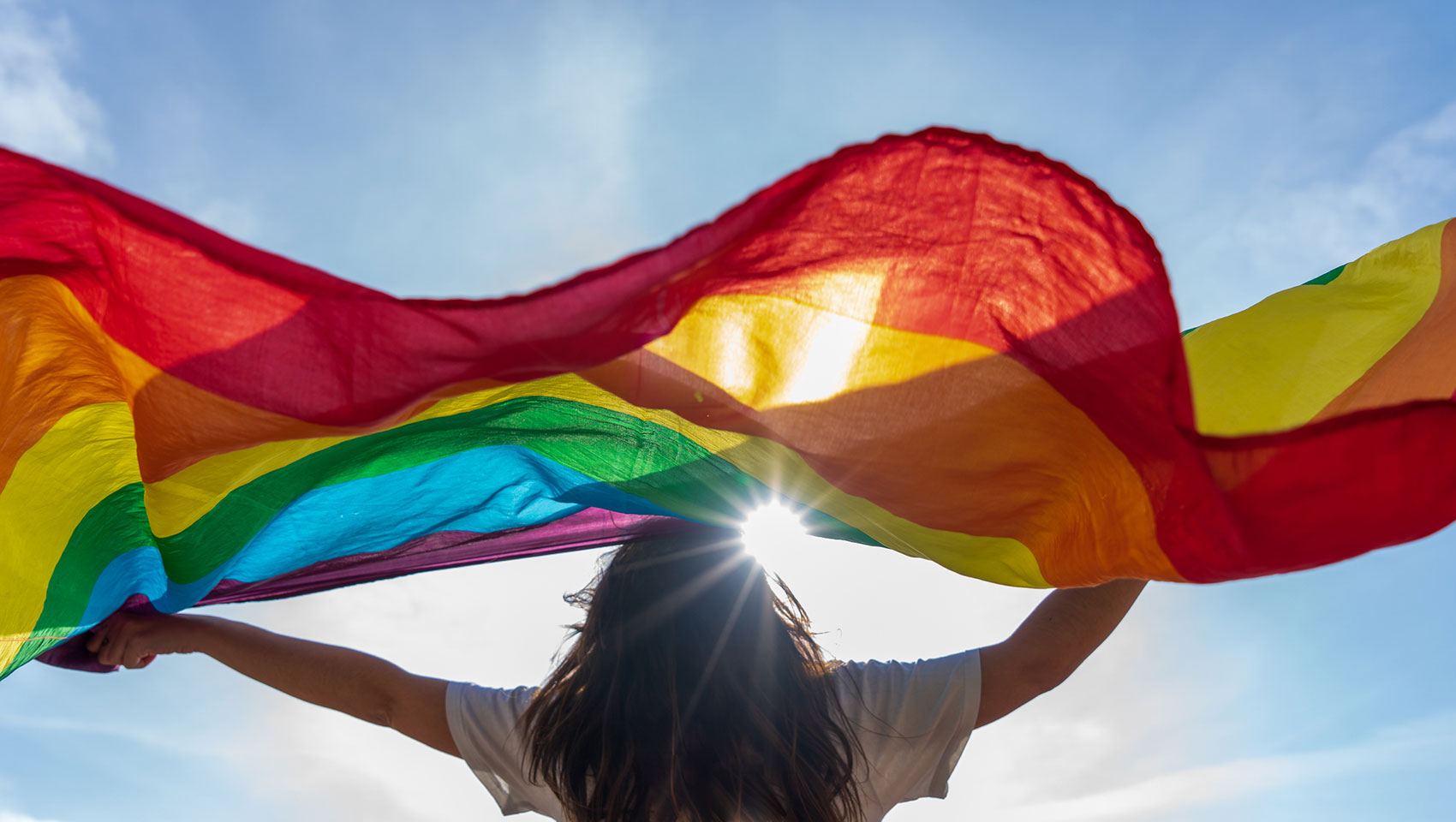 Woman holding rainbow flag in sunlight