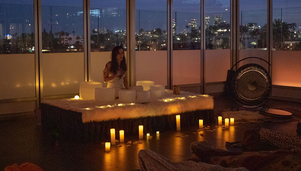 woman with sound bath bowls and candles, evening